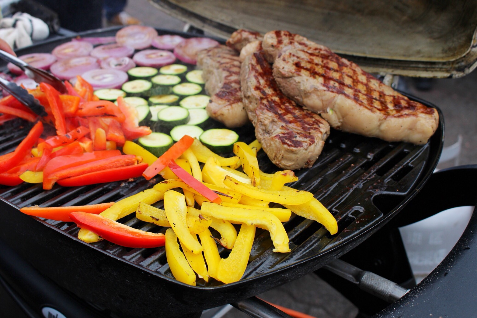 本格BBQグリルで焼かれるステーキと色とりどりの野菜
