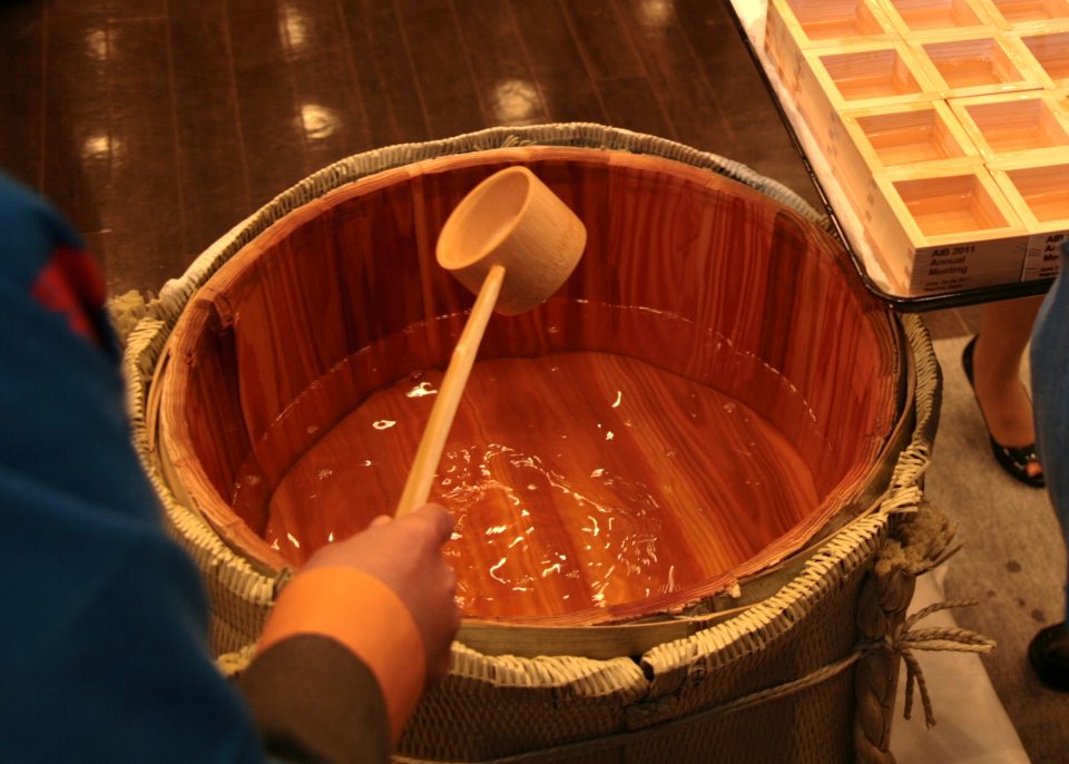 鏡開きした樽酒から柄杓でお酒を掬うところ