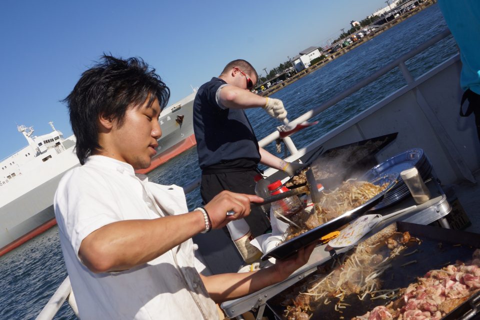 男性2人がお肉や焼きそばを焼いている