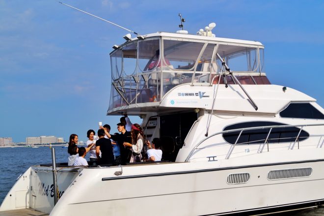 About 10 young men and women making a toast on the rear deck of *