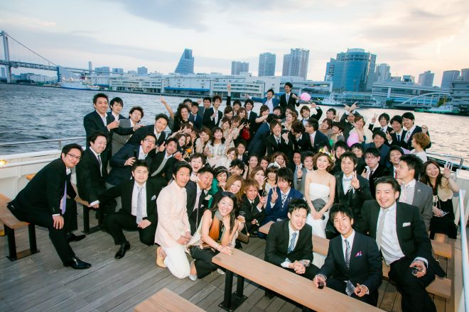 About 70 party guests after a wedding reception on the rooftop deck of the Western-style yakatabune, with Tokyo Bay in the background.