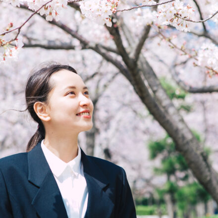 桜とスーツを着た女性
