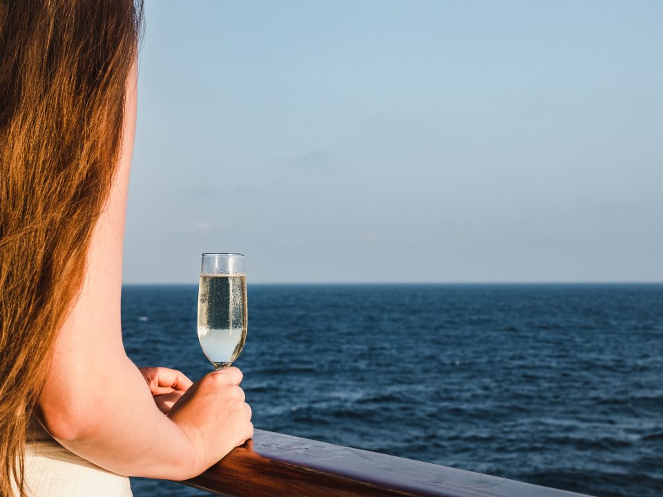 女性がグラスを持って海を眺めるシーン
